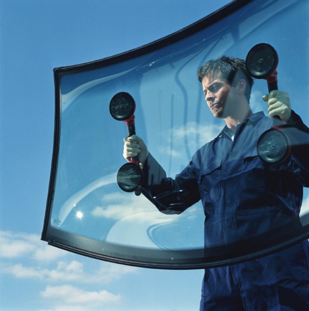 Mechanic carrying car window, view through glass